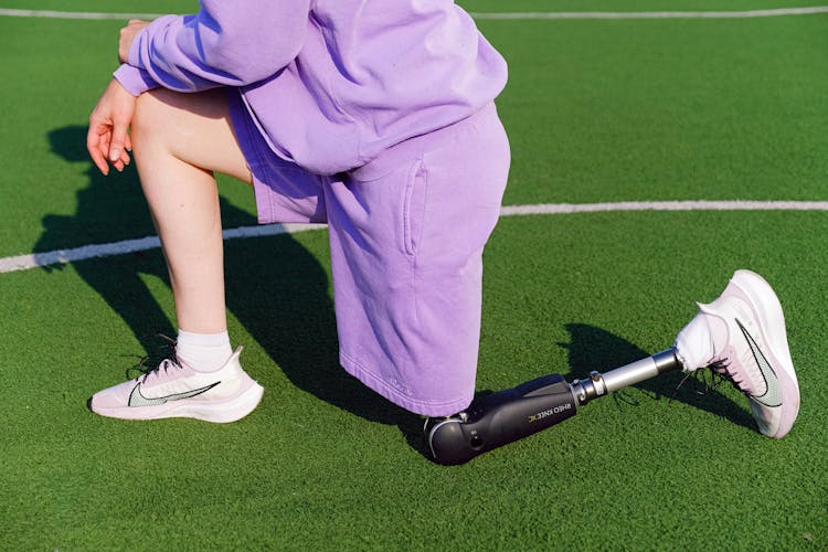 Crop Woman With Leg Prosthesis Kneeling On Court