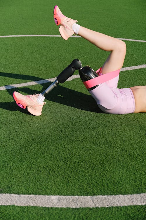 Woman with a Prosthetic Leg Exercising on a Football Pitch 
