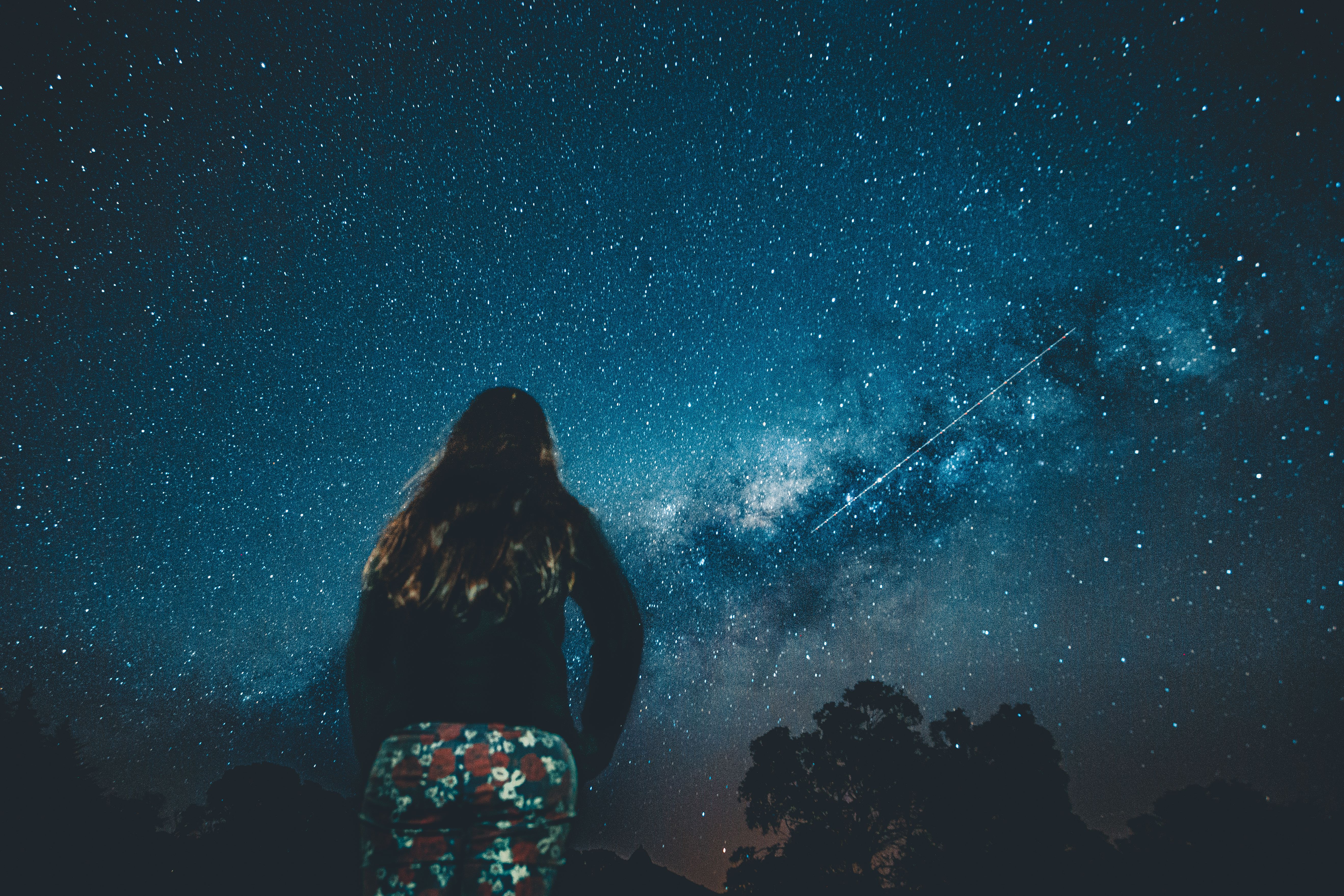 一位女士欣赏着星空，银河清晰可见，景象宁静而雄伟
