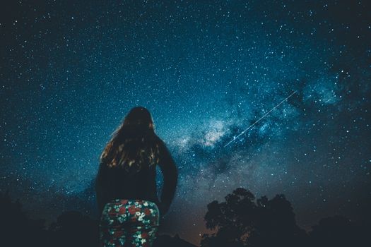一位女士欣赏着星空，银河清晰可见，景象宁静而雄伟