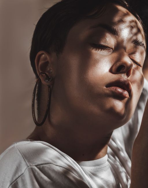 A serene portrait of a woman with closed eyes and hoop earrings, accentuated by dramatic light and shadow.
