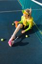 Woman in Yellow T-shirt and Black Shorts Sitting on Tennis Court