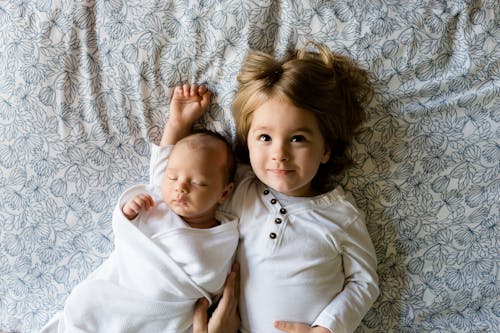 Free Baby Sleeping Beside Girl on Gray Floral Textile Stock Photo