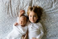 Baby Sleeping Beside Girl on Gray Floral Textile