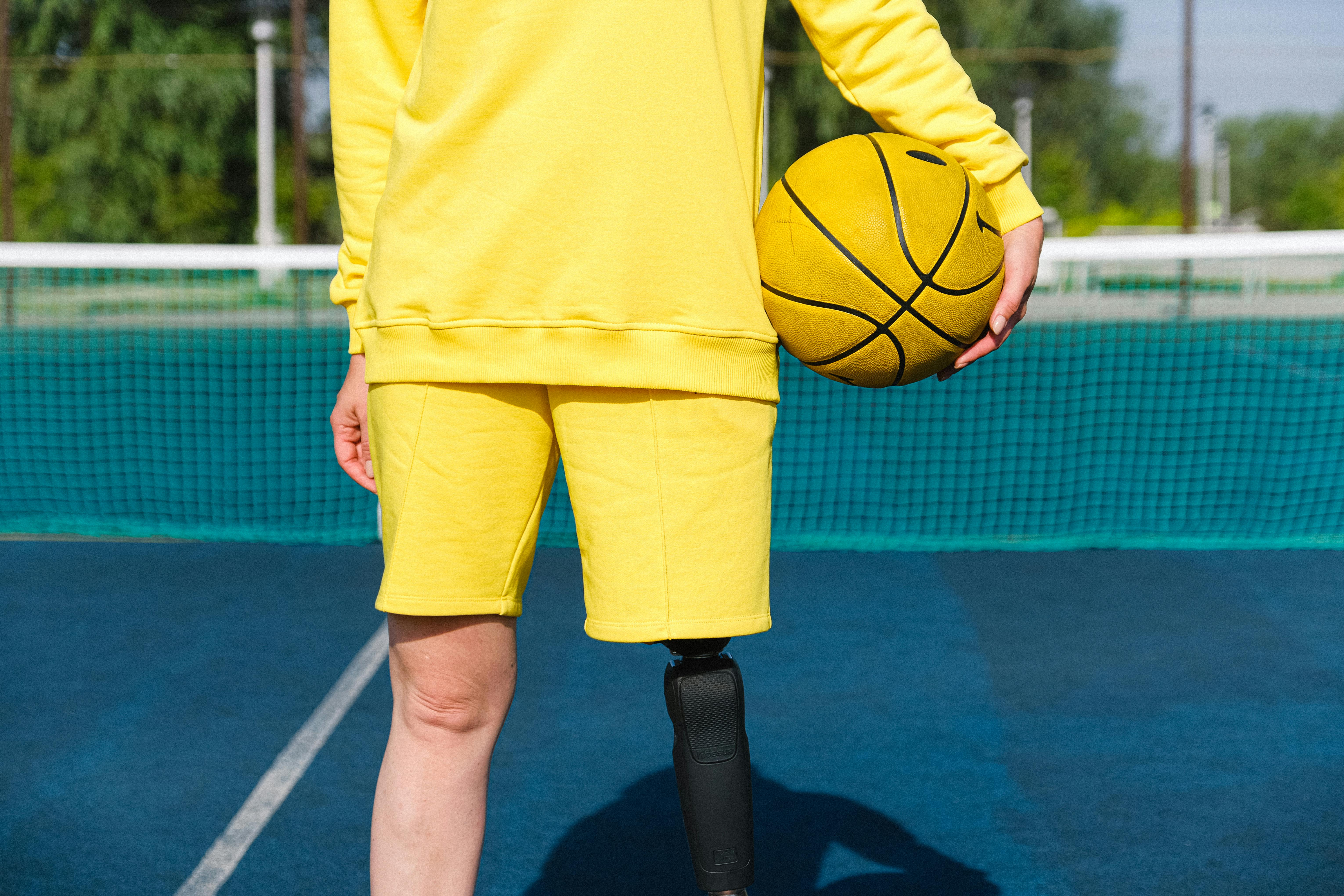 person with prosthetic leg and holding basketball ball