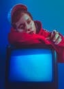 Woman in Red Hoodie Leaning on a Vintage Television