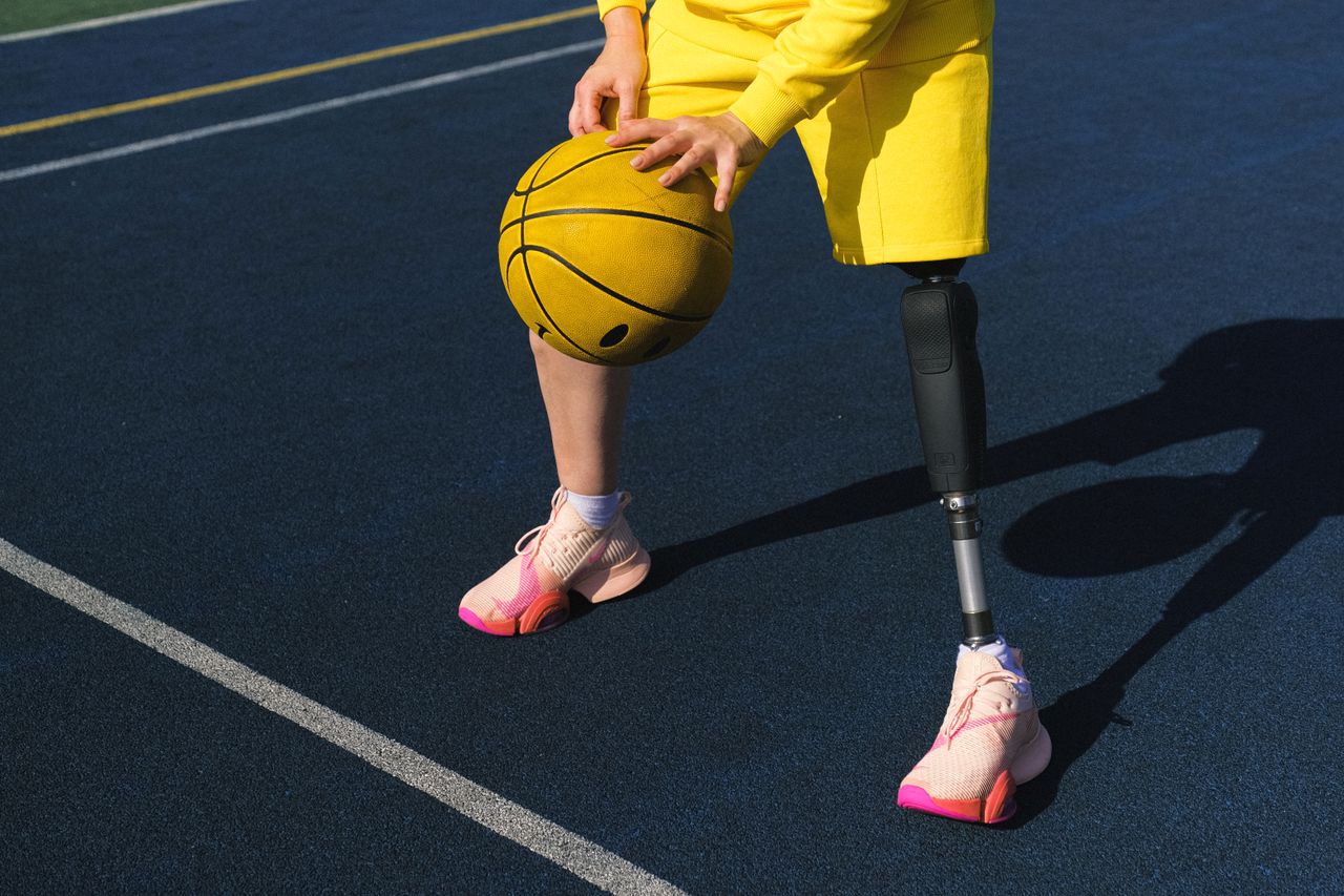 close up of an adaptive athlete with a prosthetic leg holding a basket