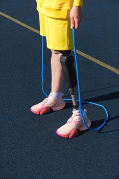 An individual in yellow clothes holds a jump rope on a track.