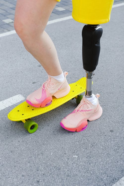 Person in Pink Nike Rubber Shoes Standing on Yellow Skateboard 