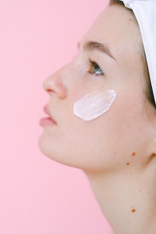 Pensive woman with cosmetic cream on face