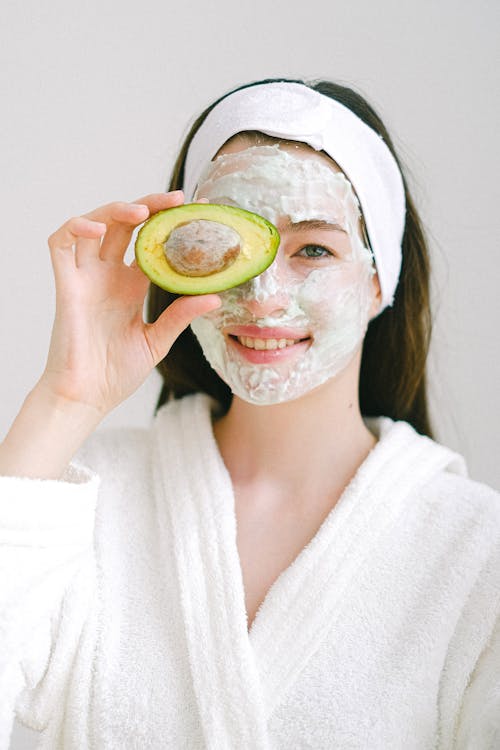 Cheerful woman with mask and avocado