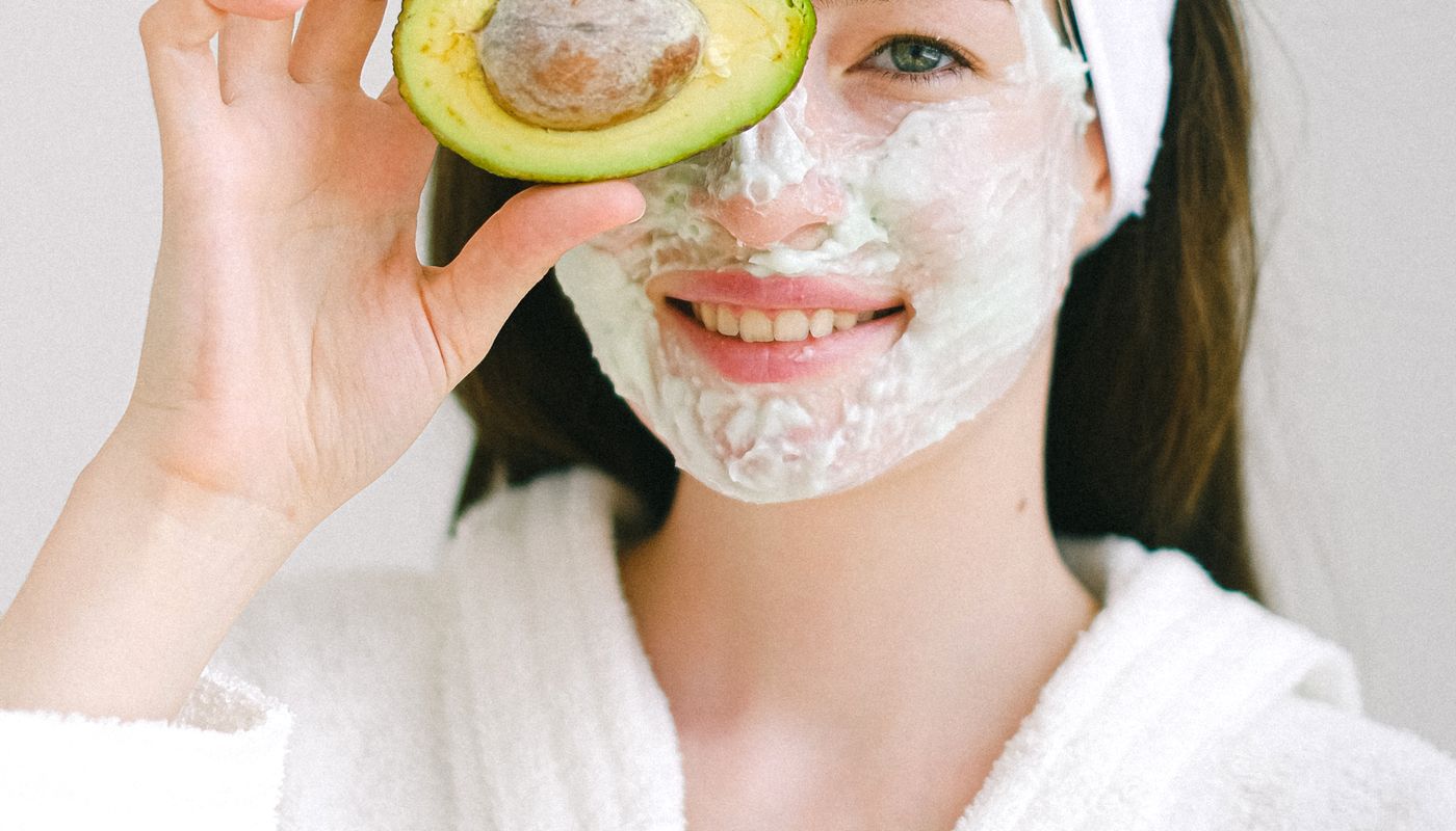 facial at home — Cheerful woman with mask and avocado · Free. Photo: Pexels