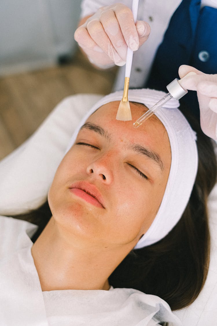 Cosmetician Applying Cosmetic Product On Customer Face