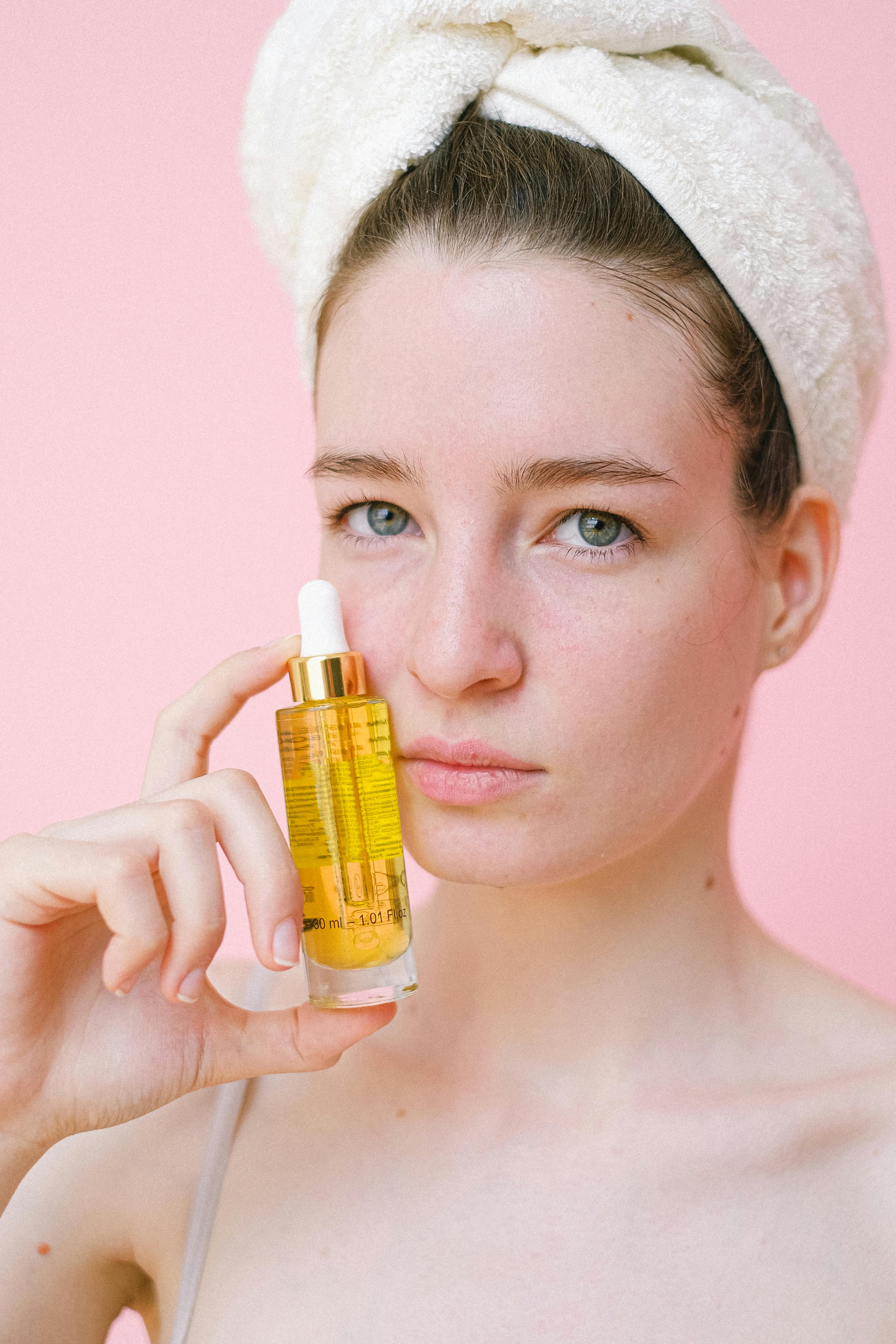 crop attractive woman with towel on head demonstrating cosmetic product