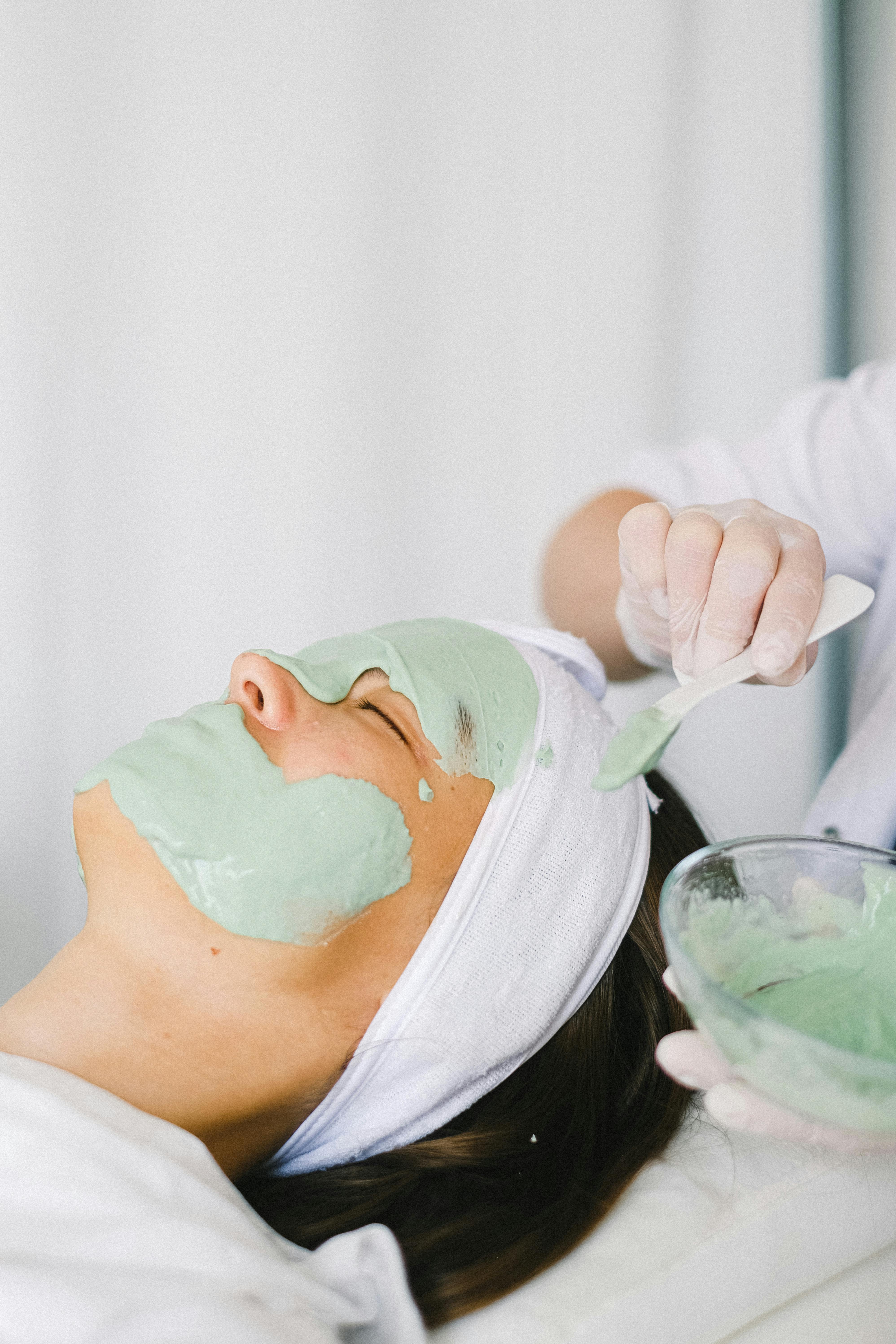 cosmetician applying facial mask on client face