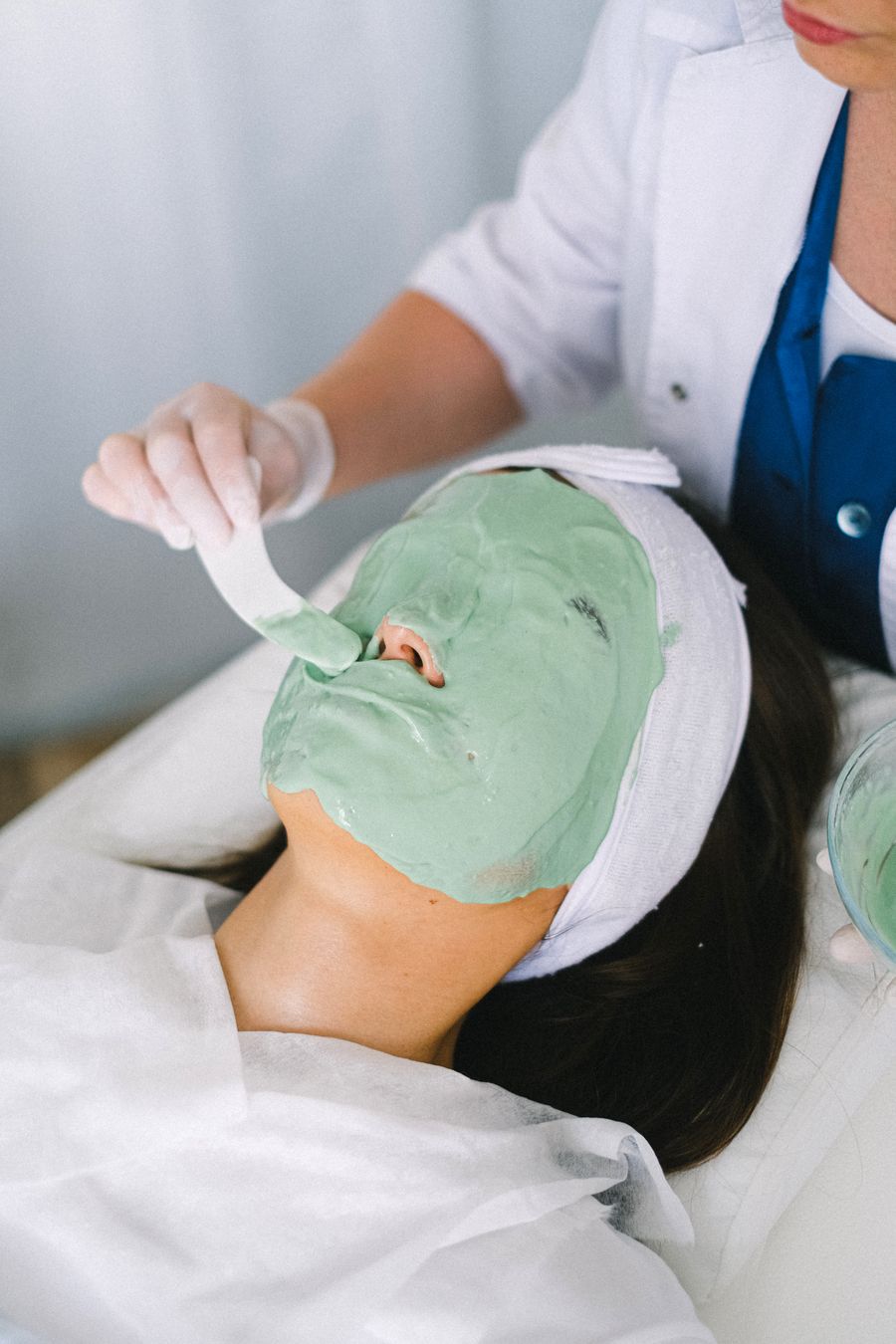 Woman enjoying a calming mask treatment in a light modern spa