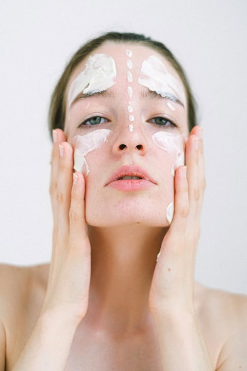 Young lady putting on cheeks cosmetic mask