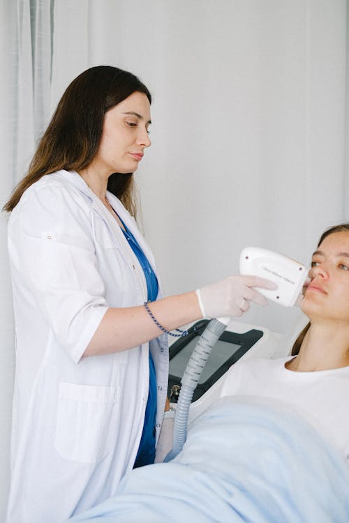 Free Cosmetologist making low level laser therapy to client Stock Photo