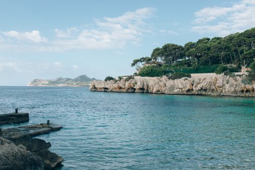 Free A serene coastal landscape featuring cliffs, blue sea, and lush greenery under a clear sky. Stock Photo