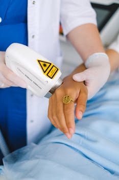 Close-up of a medical professional performing laser therapy on a patient's hand in a clinic.