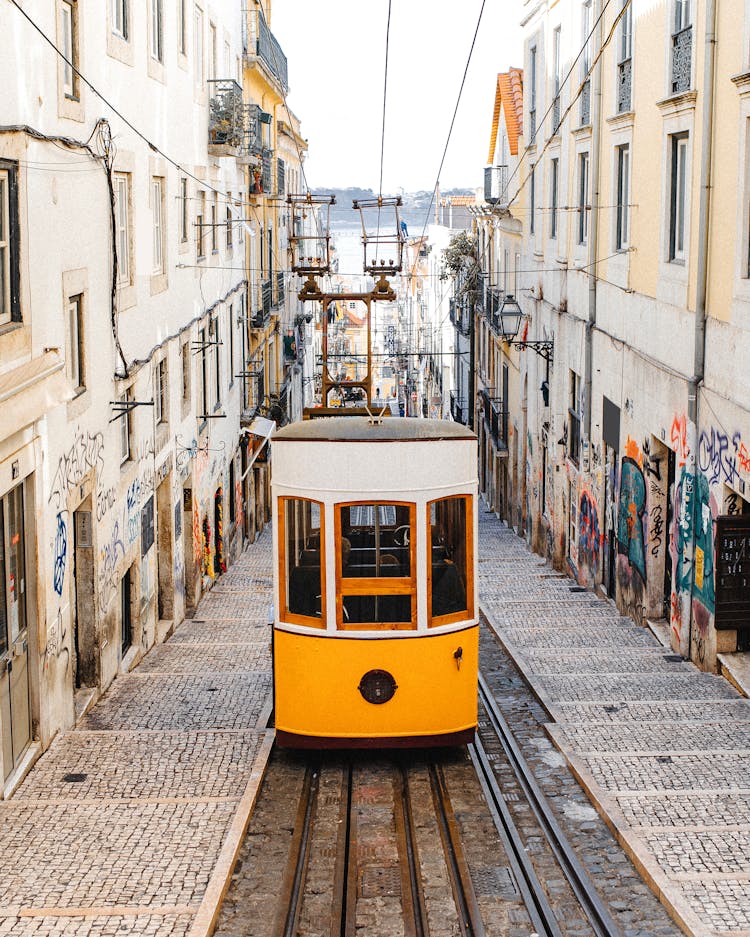 A Tram On The Street Between Buildings