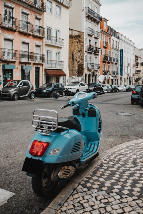 Free A picturesque urban street scene featuring a vintage blue scooter parked on a cobblestone sidewalk. Stock Photo