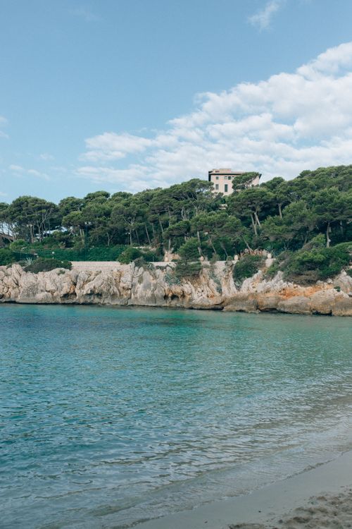 Free Idyllic coastal view with cliffs and lush trees under a bright blue sky. Stock Photo