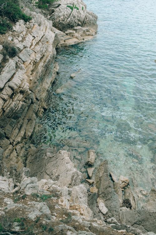 Free Stunning aerial view of rocky seaside featuring clear turquoise waters and natural rock formations. Stock Photo