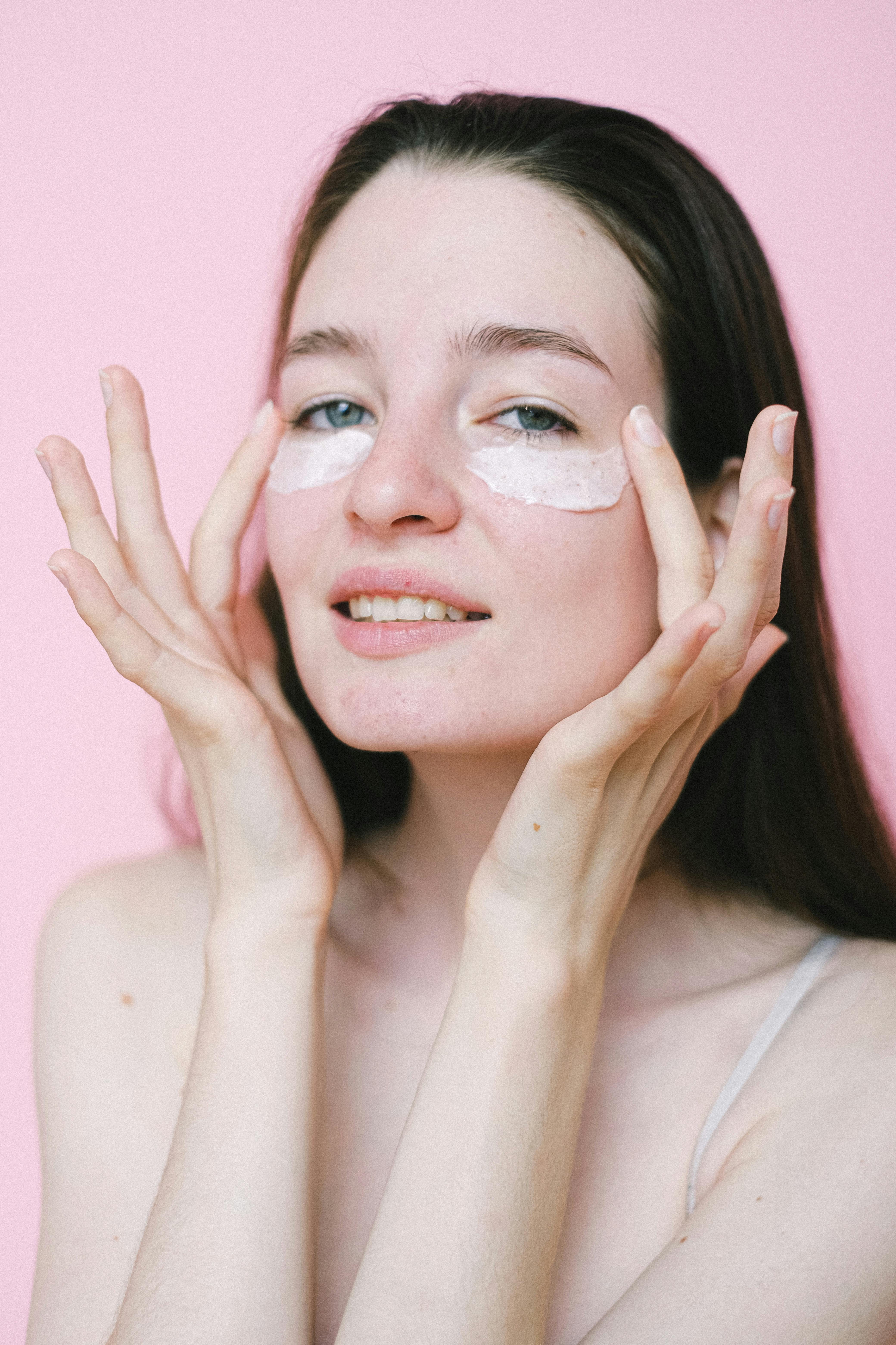 calm female applying cosmetic cream on face