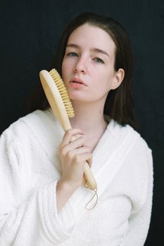 Charming female touching face with brush for anti aging massage