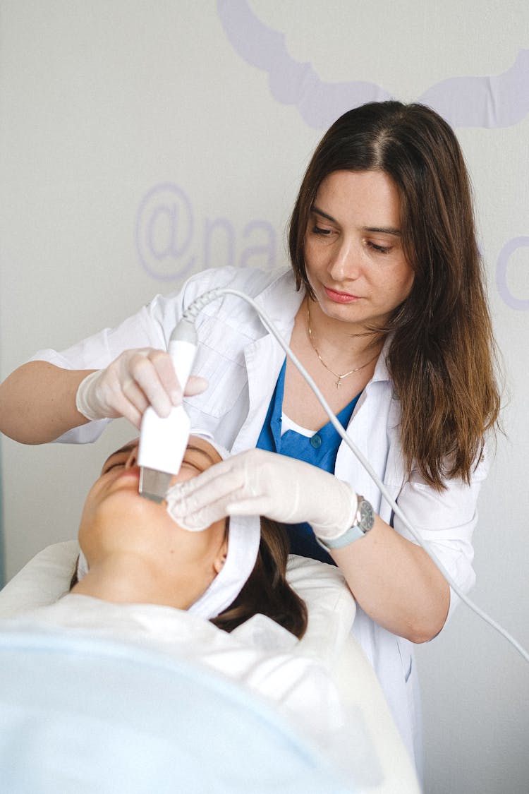 Cosmetologist Doing Ultrasonic Face Cleaning To Client