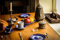 厨房餐桌场景质朴，摆满了水果、古董餐具和陶瓷餐具