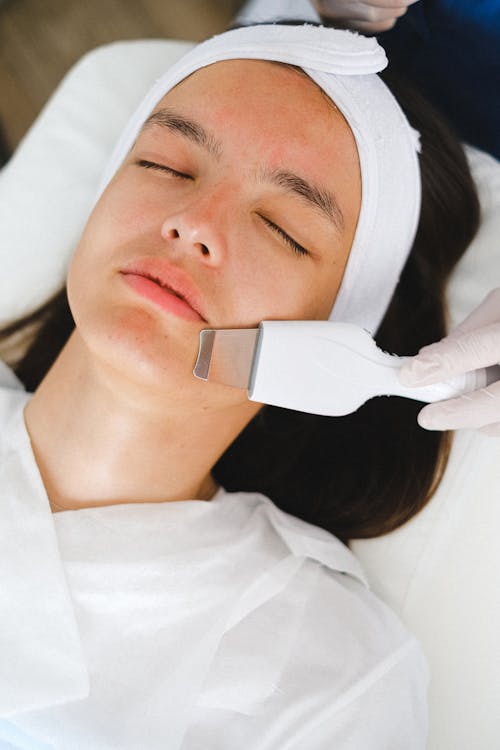 Beautician doing facial treatment procedure for patient