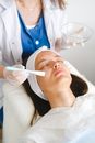 From above of crop cosmetician putting moisturizing lotion on face during beauty procedure in salon