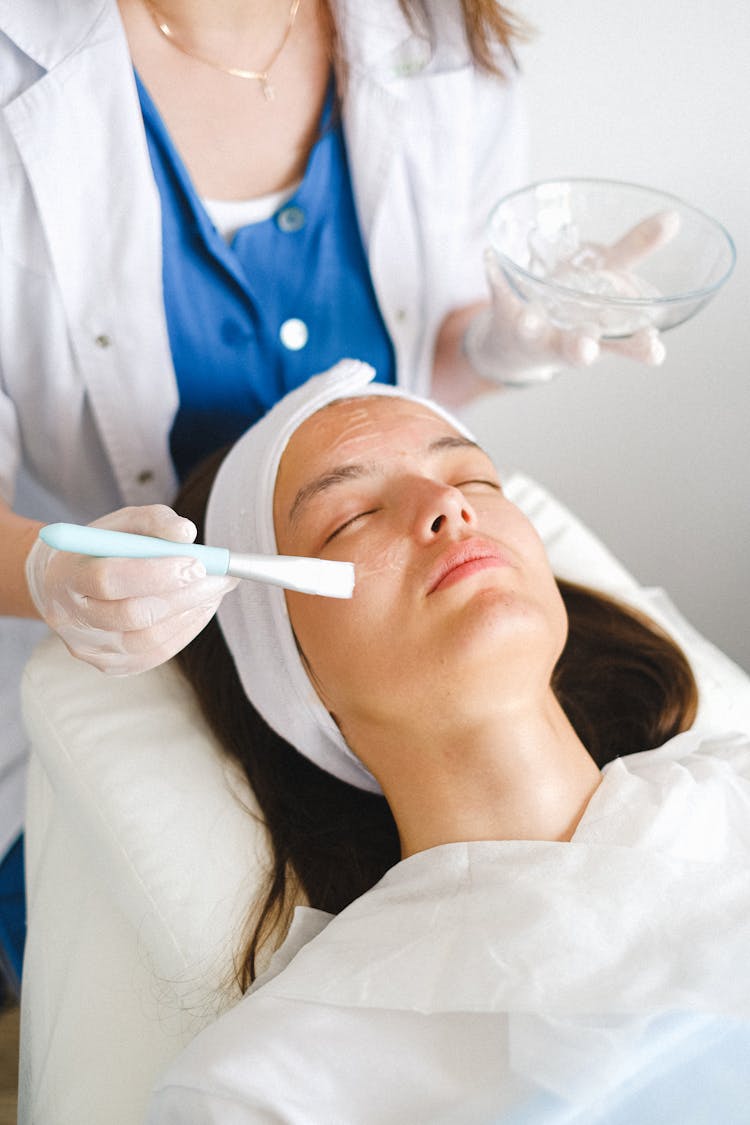 Doctor Applying Facial Cream On Client