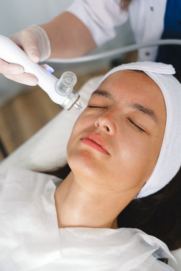 Gloved hand holding a metal-tipped probe against a reclining client's cheek