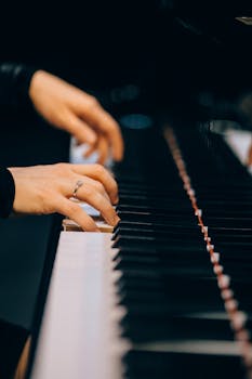 Elegant hands playing piano keys with a diamond ring visible, showcasing musical talent.