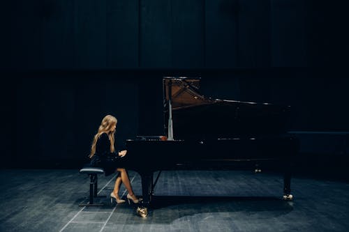 Free Woman in Black Dress Playing Piano on Stage Stock Photo