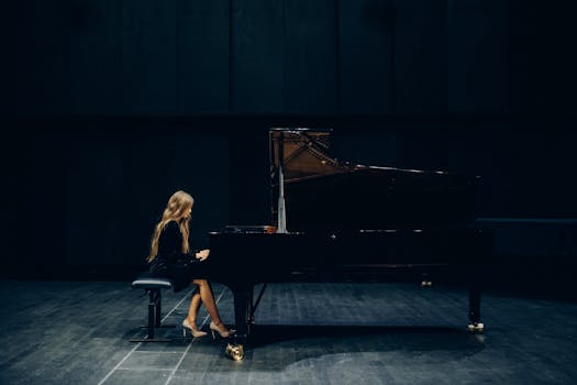 A female pianist elegantly performing on a grand piano in a dimly lit concert hall.