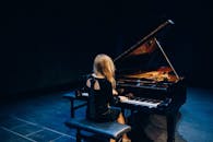 一位女音乐家在舞台上优雅地弹奏三角钢琴，营造出迷人的音乐氛围