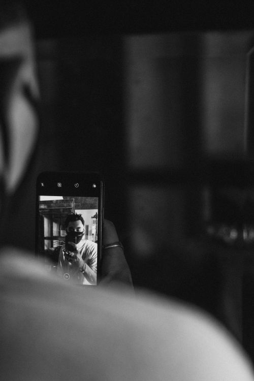 Free A man takes a monochrome selfie with his smartphone indoors. Stock Photo