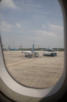 View of airplanes and tarmac from airplane window at airport.