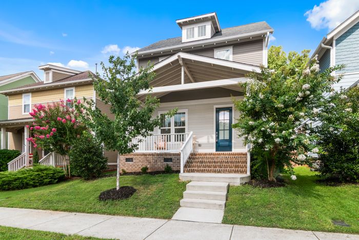 Two-storey house with a covered porch and planted front yard, photo by Curtis Adams on Pexels