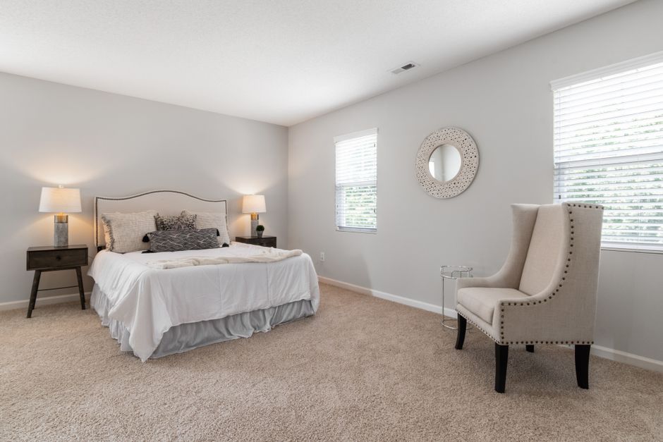 A spacious and bright modern bedroom featuring minimalistic decor and neutral tones.