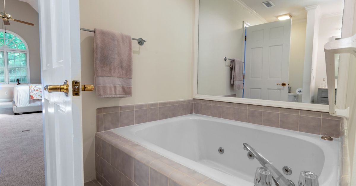 A bright and elegant bathroom featuring a large mirror and bathtub, ideal for relaxation.