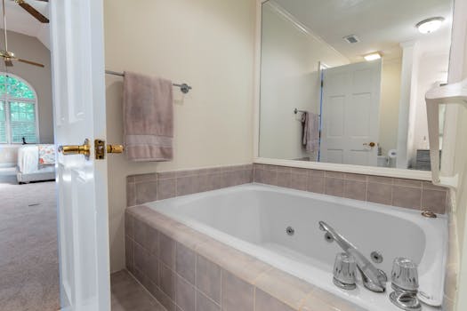 A bright and elegant bathroom featuring a large mirror and bathtub, ideal for relaxation.