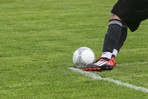 足球运动员在绿色草地上踢白灰色足球