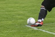 草地上，足球运动员踢球的动态镜头展现了快节奏的体育动作