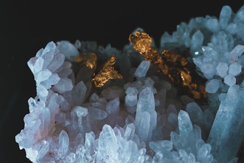 Closeup of group of colourful shiny quartz crystal cluster in light on black background