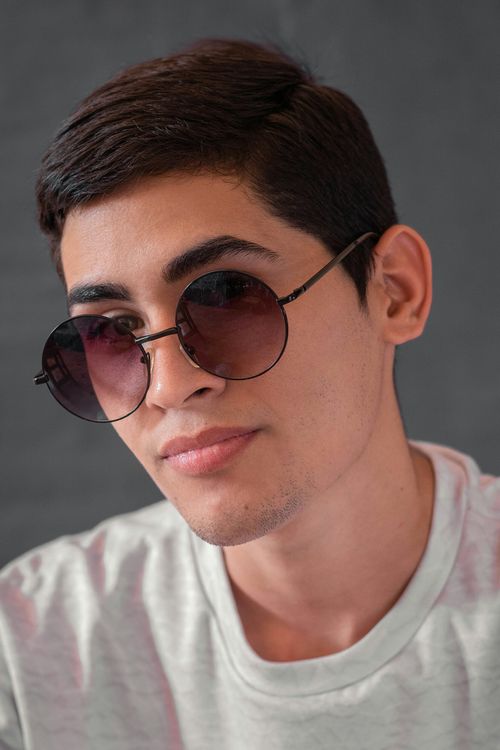 Free Close-up portrait of a young man wearing round sunglasses and a casual shirt. Stock Photo